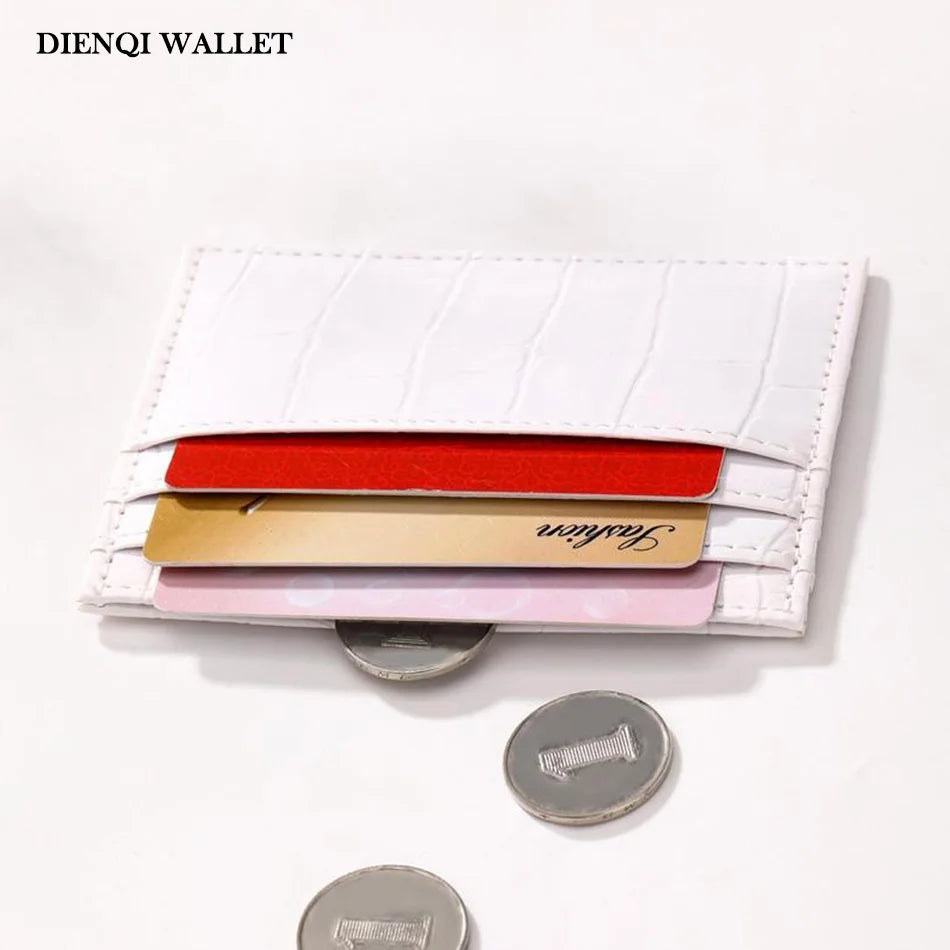 A white leather wallet with a crocodile pattern featuring multiple colored cards and a metal fastener.