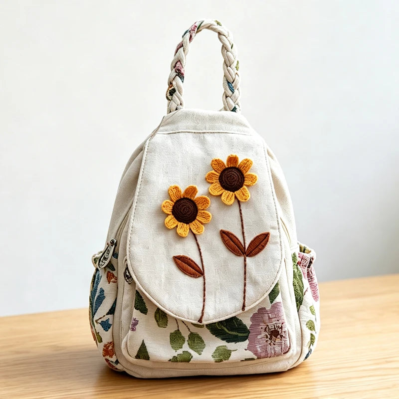 A light beige linen backpack featuring three embroidered orange and purple flowers.