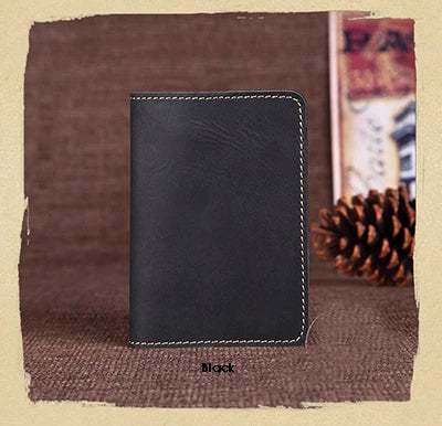 A black genuine leather passport wallet with card holders resting on a brown textured surface.