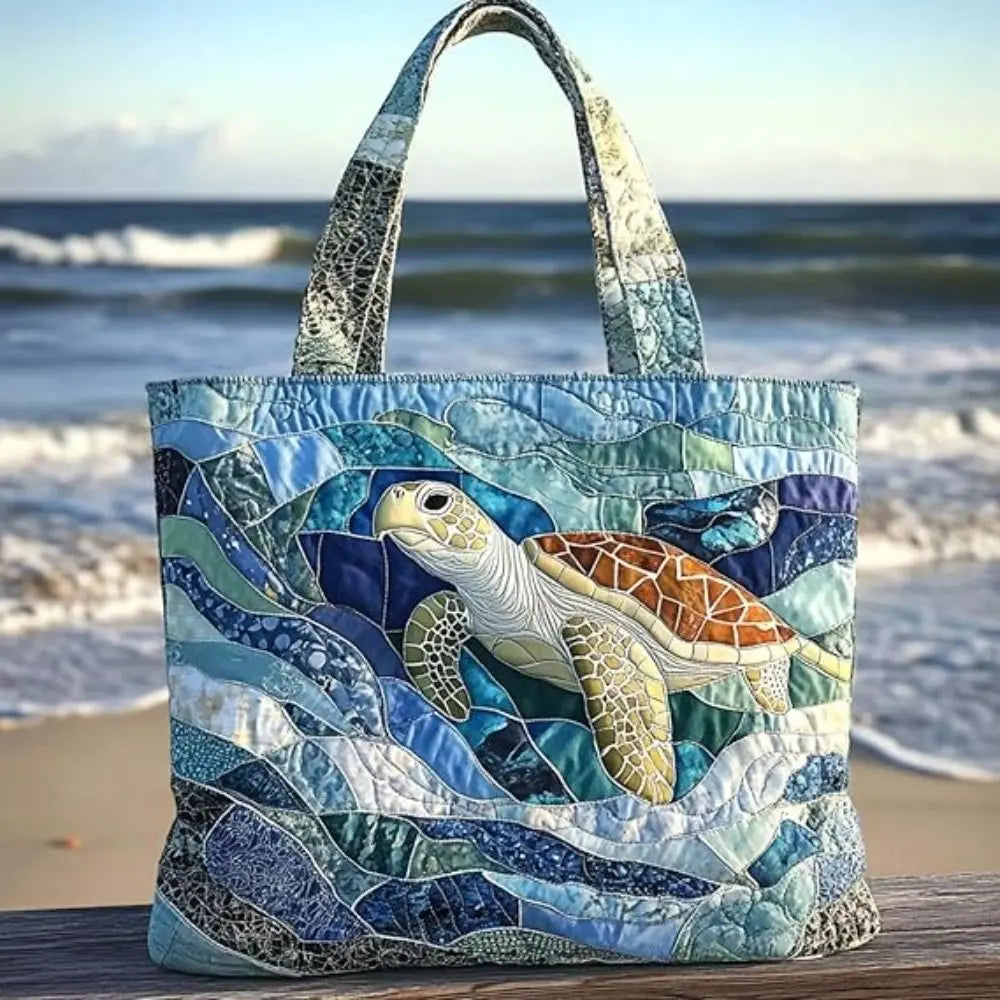 A quilted canvas tote bag featuring a detailed illustration of a sea turtle in shades of blue, green, and yellow.