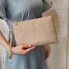 Una mano sostiene un bolso de cuero sintético floral beige contra un vestido azul claro.