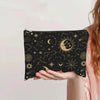 Una mano sostiene una bolsa de almacenamiento con cremallera de lona negra decorada con diseños celestiales dorados como la l