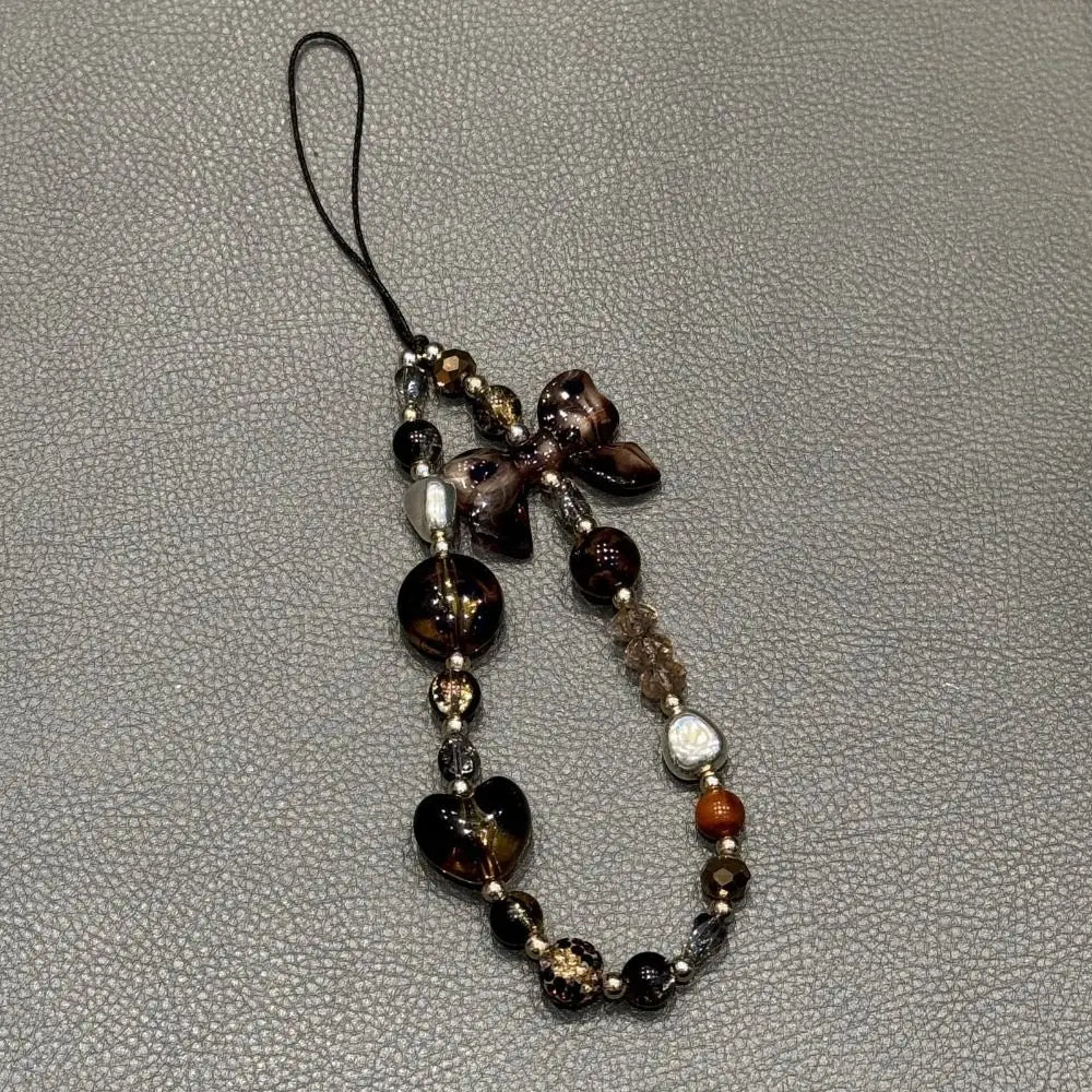 A leopard print bowknot phone lanyard featuring various heart-shaped beads and decorative elements.