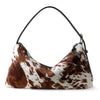 A brown and white spotted vintage horsehair and cowhide crossbody bag with a thin black strap.