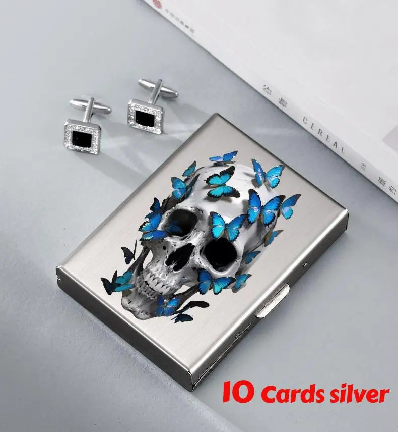 Silver card holder featuring a skull design with blue butterflies, alongside matching silver card clips.