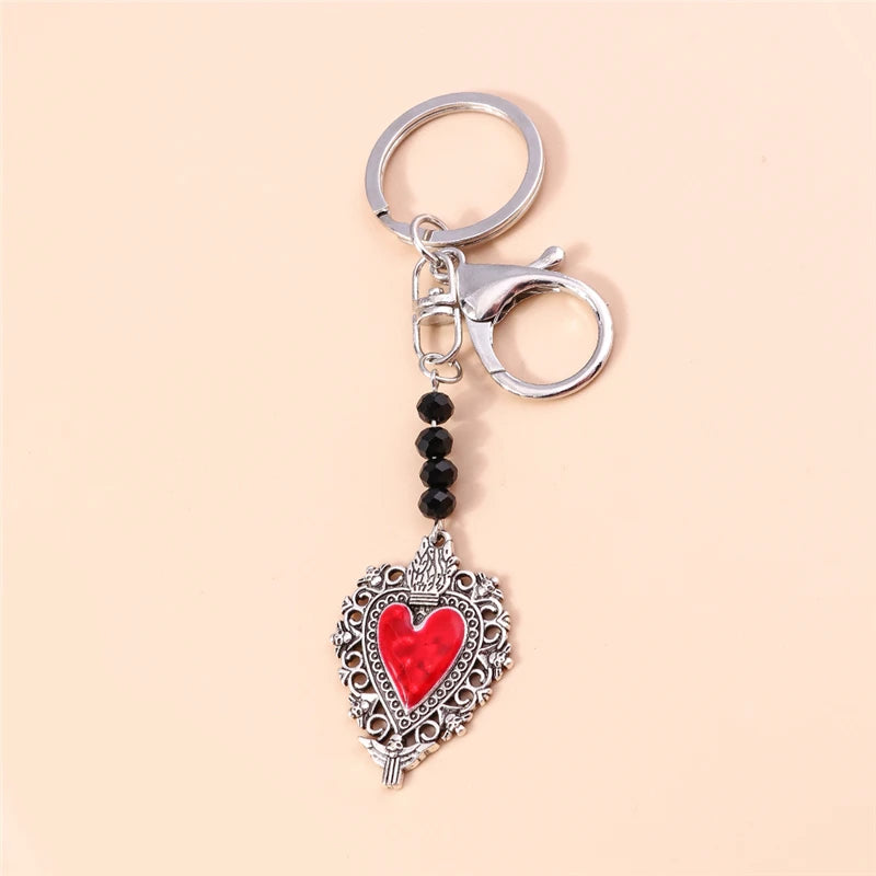 Silver keychain featuring a heart pendant with red stones and intricate detailing.