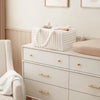 A white flannel diaper caddy organizer sits on a light wood dresser with folded white towels.