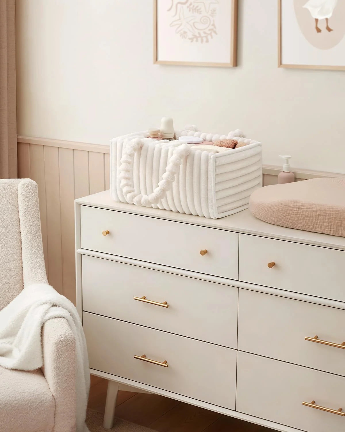 A white flannel diaper caddy organizer sits on a light wood dresser with folded white towels.