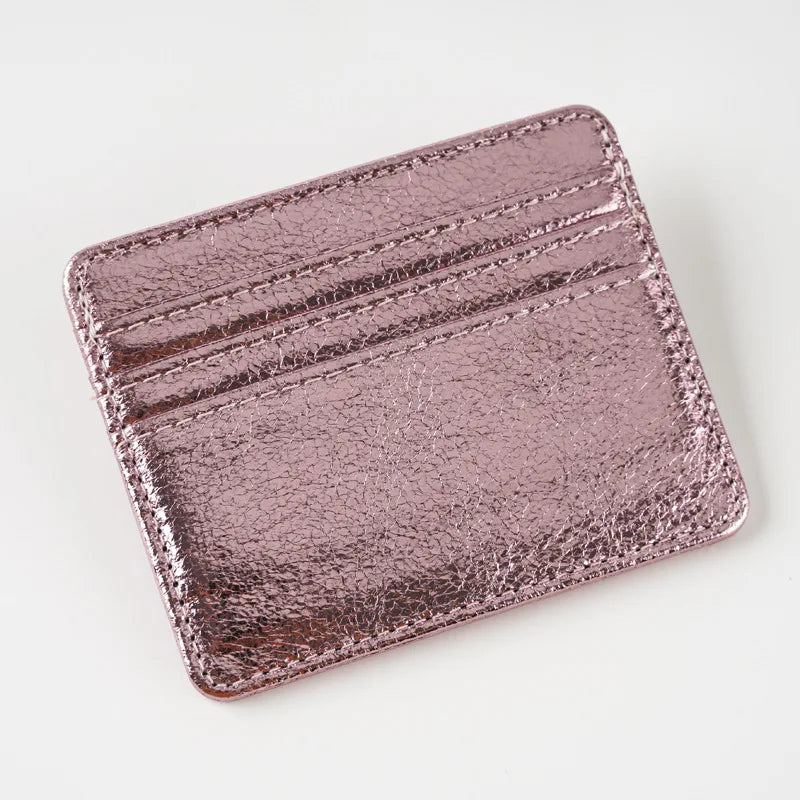 A close-up of a rose gold colored slim leather mini wallet card holder with embossed lines.