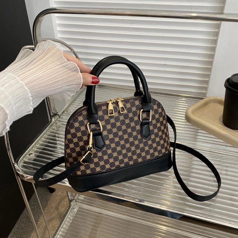 A black patterned fashion shell shoulder crossbody bag resting on a silver metal shelf.