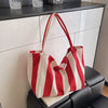 A red and white striped canvas tote bag with a handle is displayed on a dark surface.