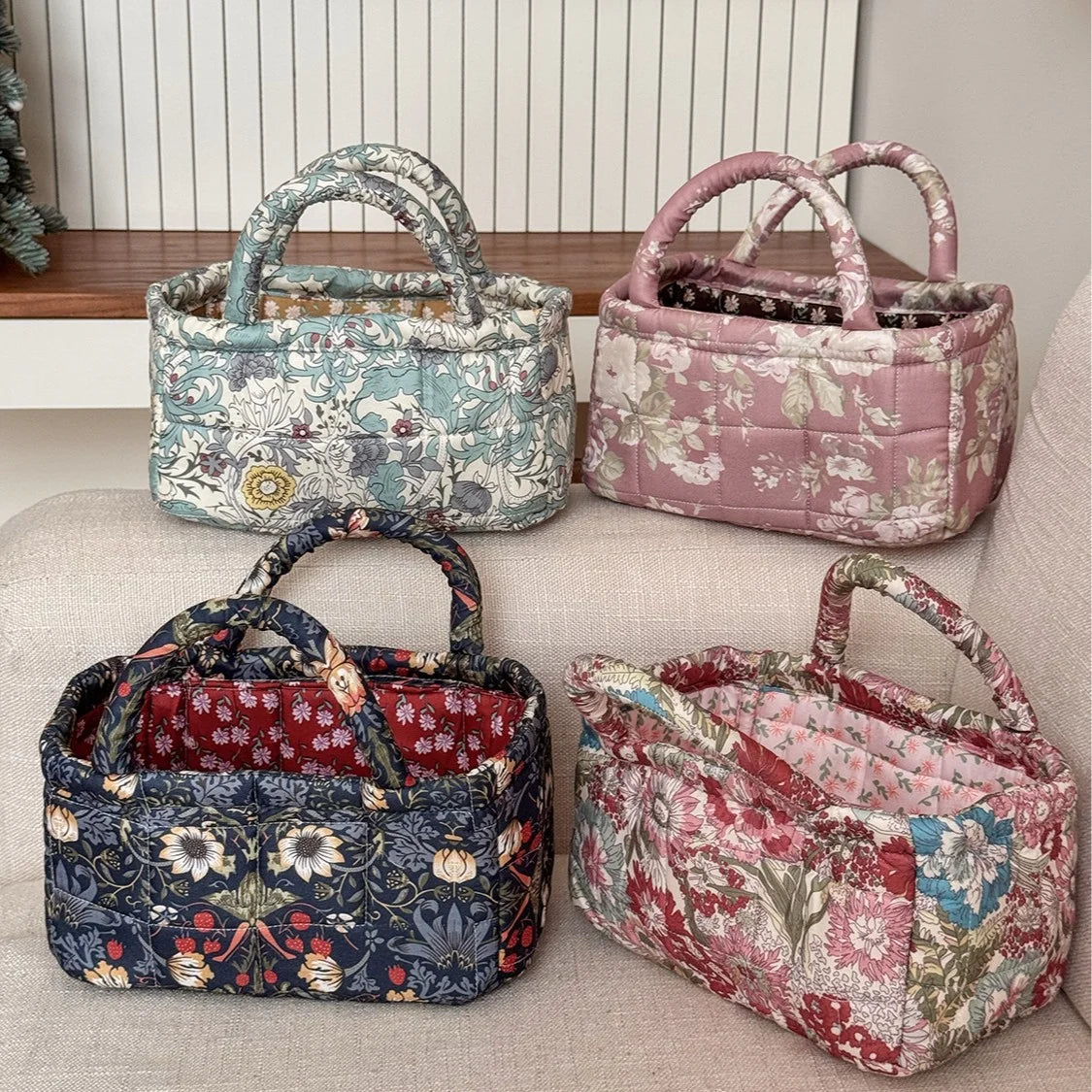 Three quilted fabric storage baskets in various floral patterns and pink tones displayed on a light surface.