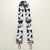 A black and white cow print textile replacement bag strap with gold-toned hardware.