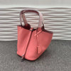 Pinkes Leder-Bucket-Bag mit rosa Träger auf grauem Untergrund.