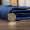 A dark blue leather clutch wallet folded and displaying a coin.