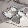 Silver acrylic bow clasp mini handbag with a chain strap resting on a gray fabric.