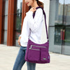 Eine Frau hält eine lila wasserdichte Nylon-Crossbody-Tasche mit Reißverschluss über der Schulter im Freien.