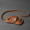 A brown PU leather storage case for eyeglasses with a leather strap and metal arms.