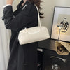 A woman wearing a black coat holds a cream glossy PU leather tote bag with dual straps.
