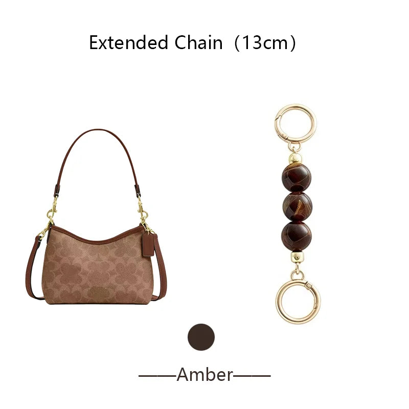 A brown suede pouch attached to an extended gold chain with dark amber beads.