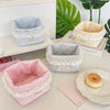 Light pink fabric storage basket with a heart and bow detail shown on a white surface.