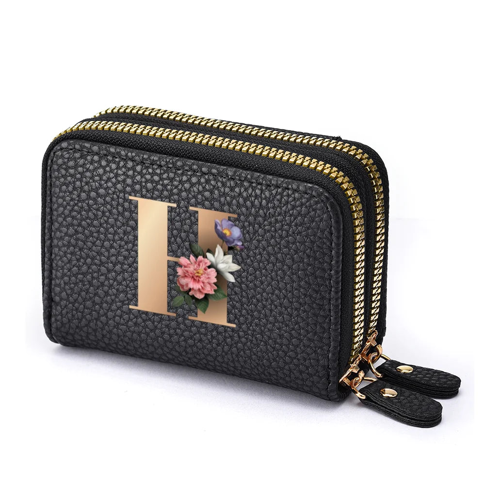 Black faux leather mini wallet with a gold letter H print and floral embellishments and a double zipper