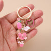 A gold-toned enamel heart keychain featuring a rose, a love heart, and a heart balloon.