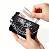 Eine Hand hält eine schwarze durchsichtige Tasche mit Münzen und Karten, wobei eine rosa Banknote sichtbar ist.