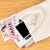 A beige canvas tote bag with a delicate gold-rimmed pair of eyeglasses resting inside.