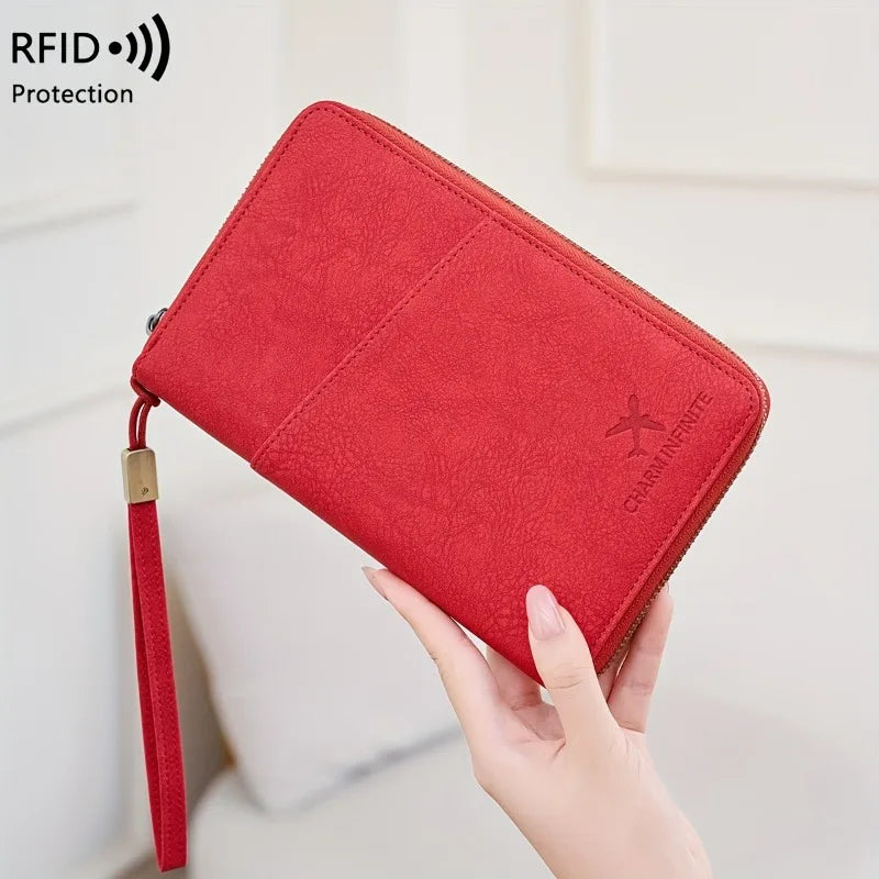 A hand holds a red RFID-blocking passport wallet with a wrist strap, showing the protection feature.