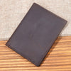 A dark brown genuine leather bifold card holder resting on a wooden surface with a burlap background.