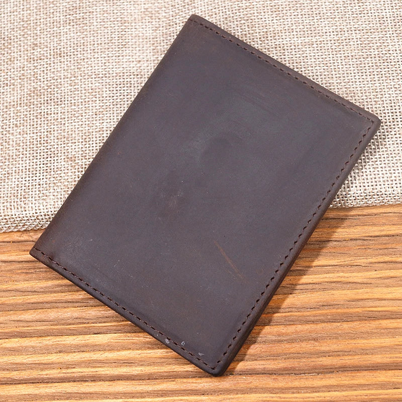 A dark brown genuine leather bifold card holder resting on a wooden surface with a burlap background.