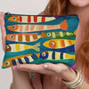 Une main tient un sac de maquillage vintage avec des motifs de poissons colorés pour l'organisation des voyages et du maquill