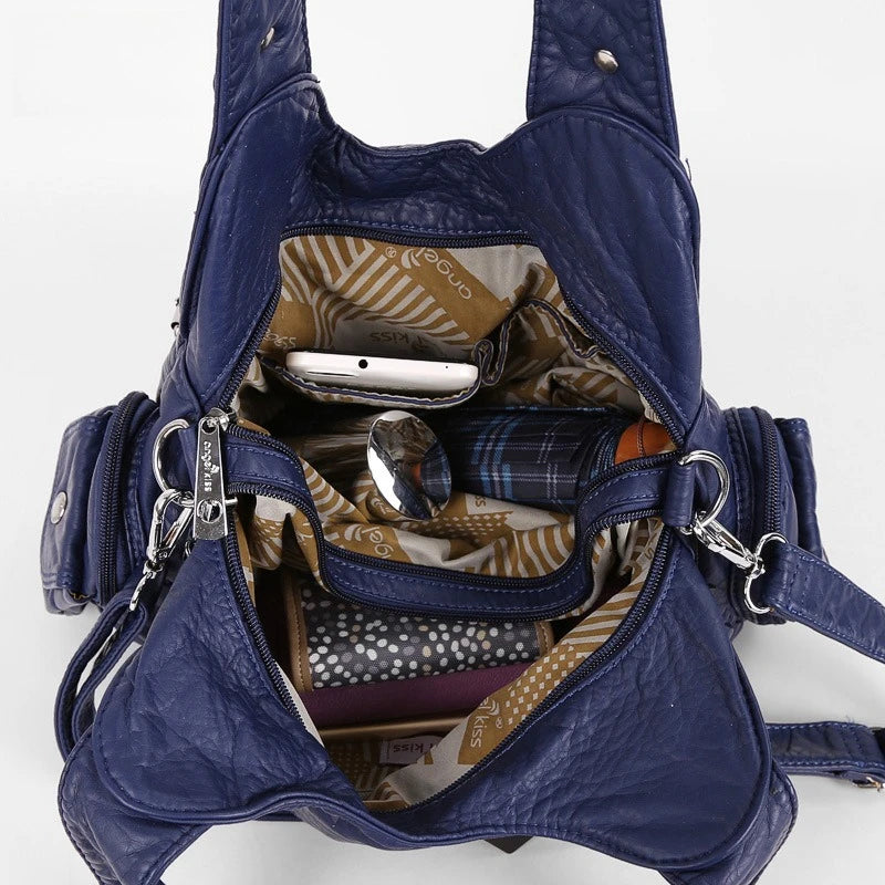 A dark blue vintage PU leather hobo shoulder bag with a zippered interior showing a smartphone and small accessories.