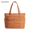 Sac fourre-tout matelassé beige avec une longue poignée, présenté sur fond blanc.