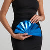 A woman wearing a black strapless dress holds a bright blue acrylic chain crossbody bag.