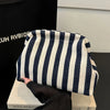 A striped crochet tote bag with a shell accent is displayed on a light surface.
