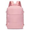 A pink compact travel backpack with pink straps and multiple storage compartments.