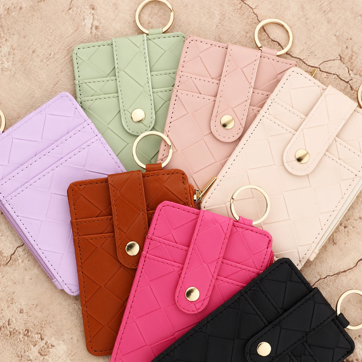 A collection of pink, green, purple, and brown PU leather card holder wallets with gold rings