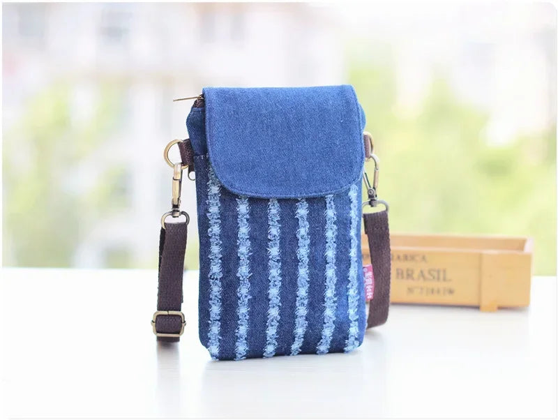 A blue denim mini messenger bag with a flap and strap is shown on a white surface.