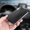 A hand holds a black carbon fiber card holder wallet with a textured pattern.