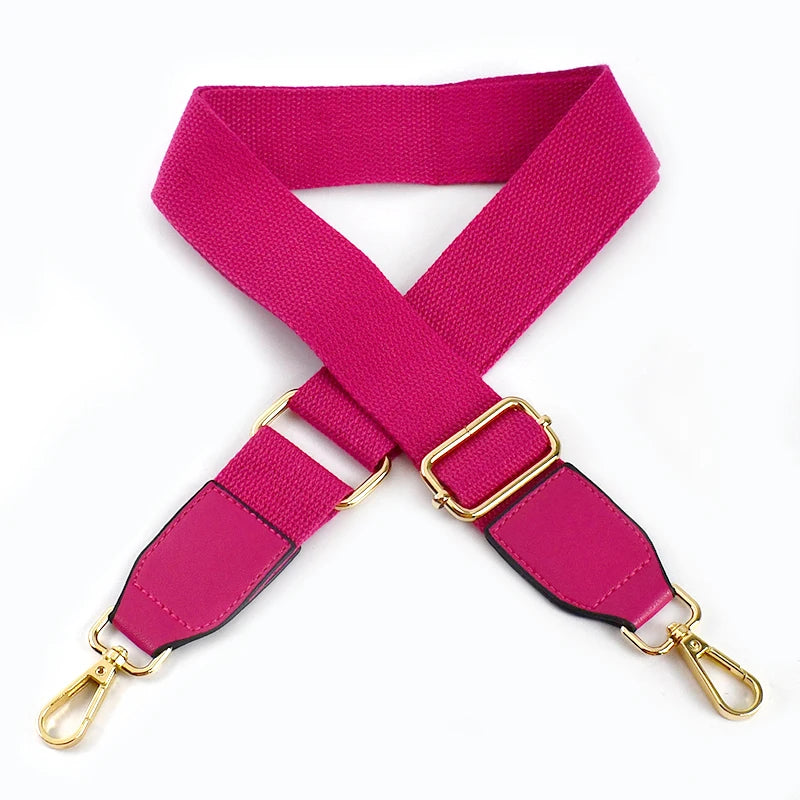 A magenta canvas cotton bag strap with gold-toned metal hooks shown in an X-shape.