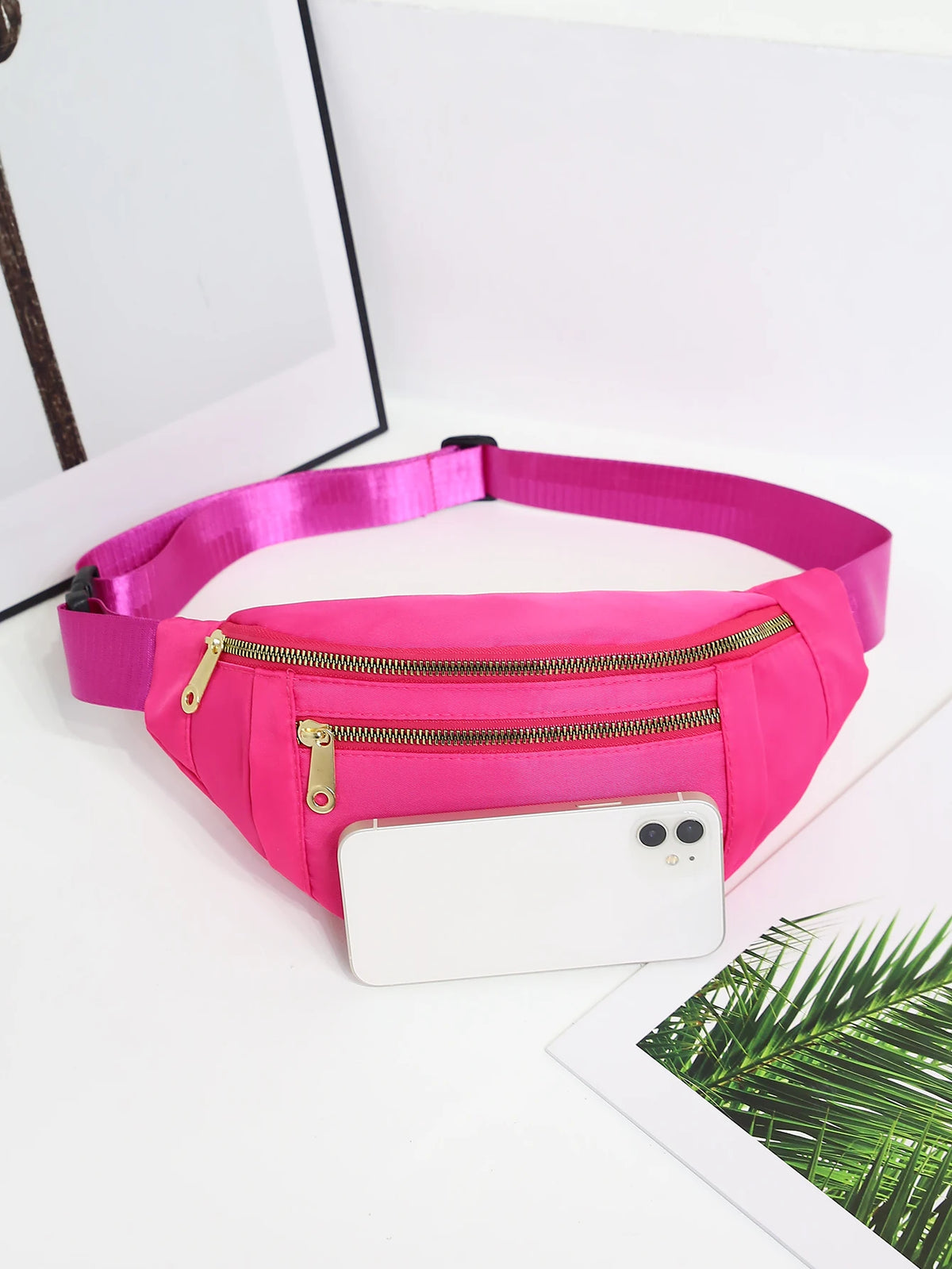 A bright pink multi-layer sports waist bag with a zipper, resting on a white surface.