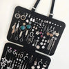 A black wall-mounted jewelry organizer featuring various silver and gemstone-colored earrings and necklaces.