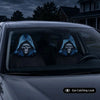 Two people wearing gothic skull headrest covers with a blue glow design inside a car.