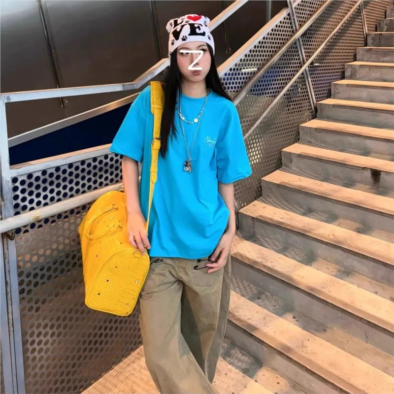 A young woman wearing a blue t-shirt and khaki pants is walking down an outdoor staircase, carrying a yellow tote bag.