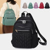 A black quilted waterproof women's travel backpack displayed next to several colored backpacks.