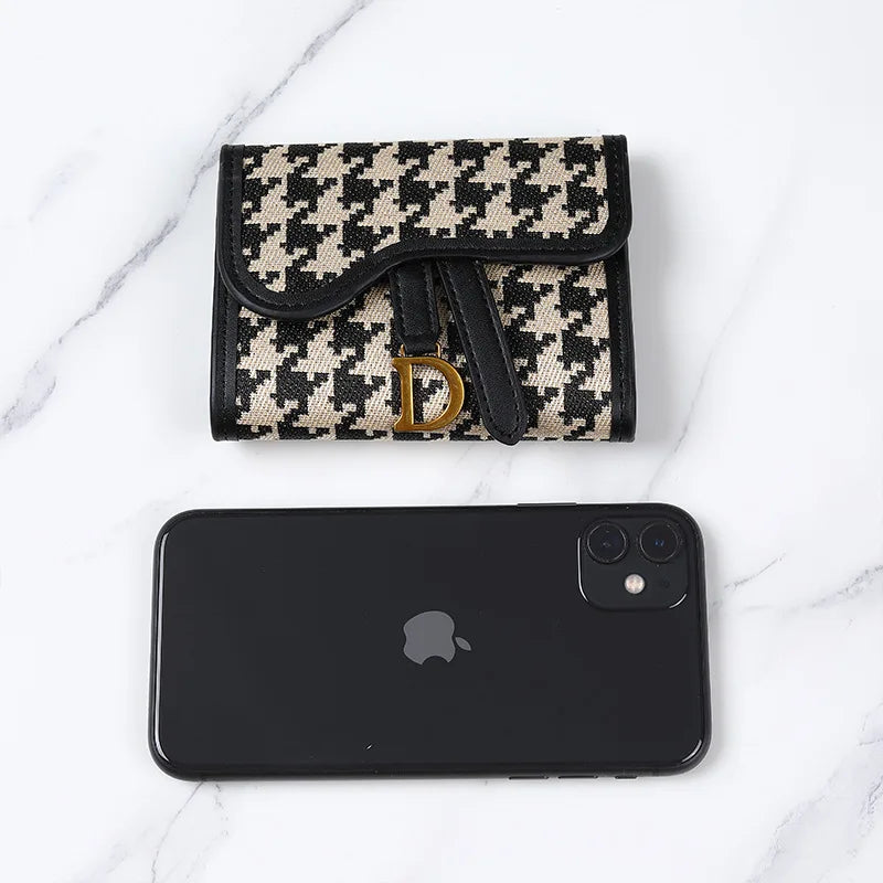 Portefeuille avec motif houndstooth noir et blanc à côté d'un smartphone noir.