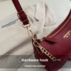 A close-up of a maroon leather shoulder bag featuring a gold hardware hook and chain detail.