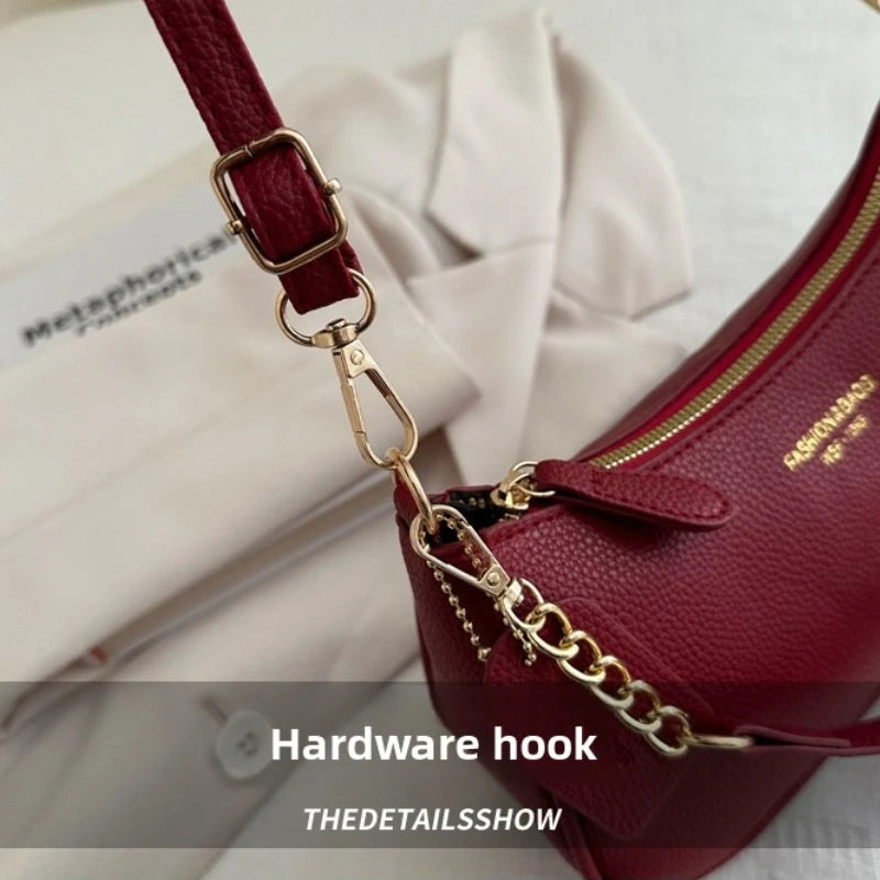 A close-up of a maroon leather shoulder bag featuring a gold hardware hook and chain detail.
